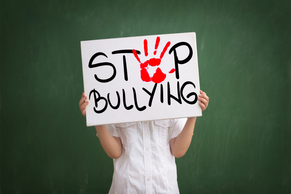 Child holding up stop bullying sign.